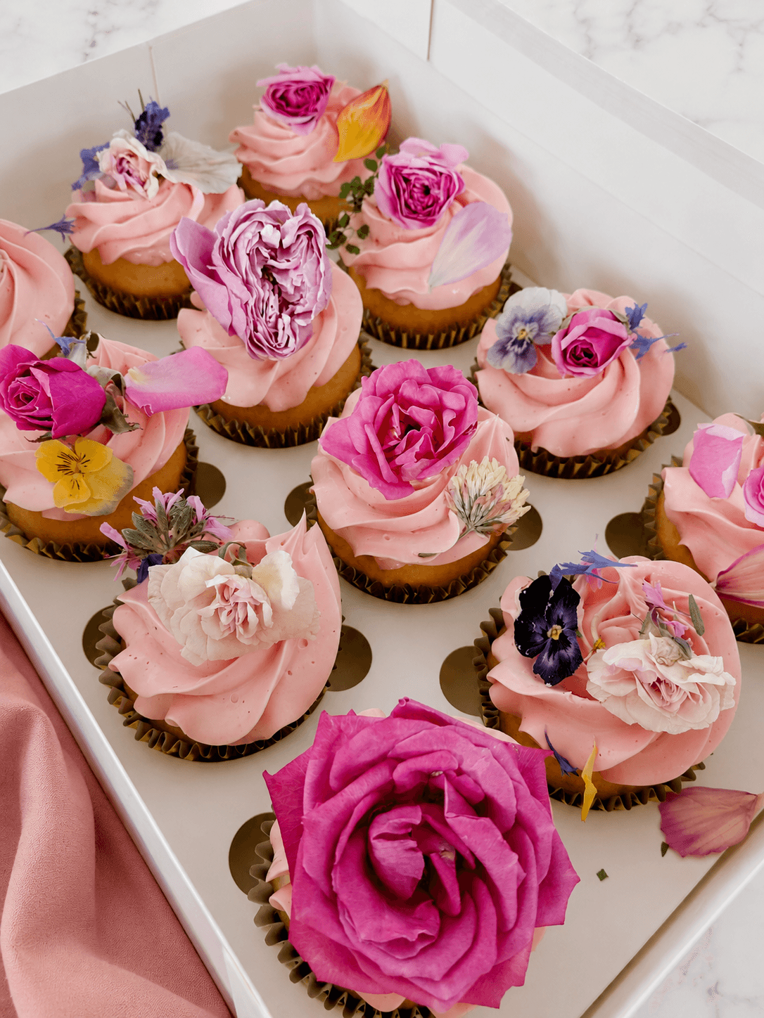 Vanilla cupcakes in pink with edible pink flowers on top
