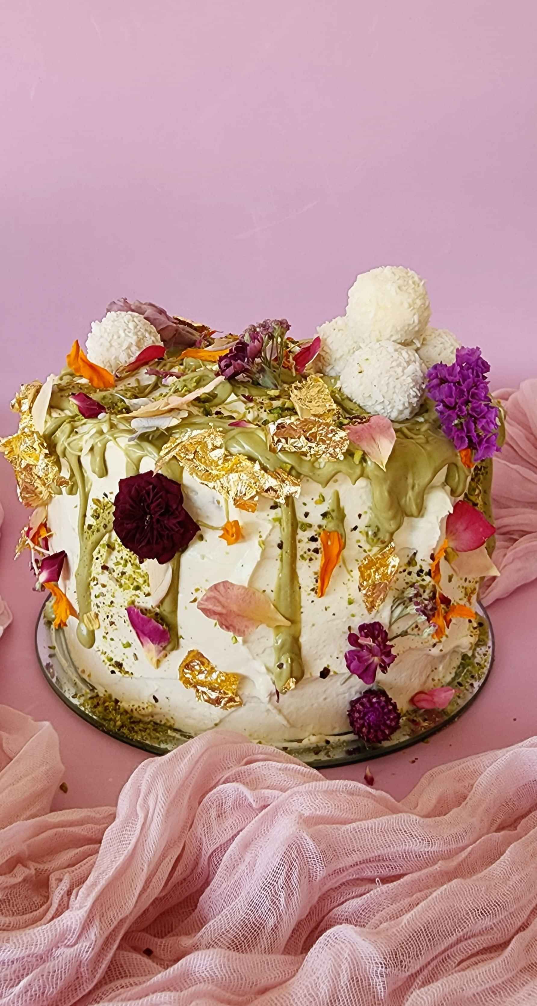 A mini vanilla and pistachio cake with edible flowers and raffaello