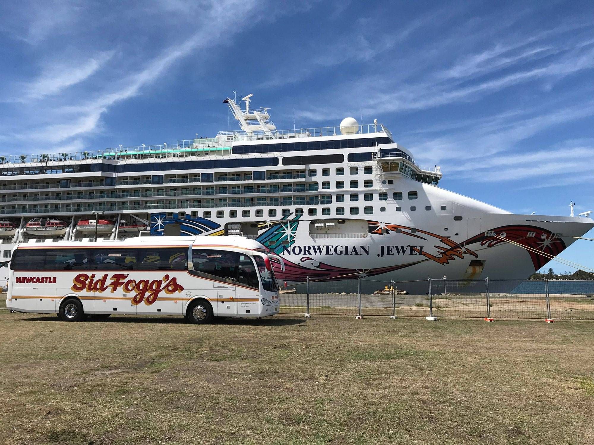 Sid Fogg's group charter bus parked beside a cruise ship