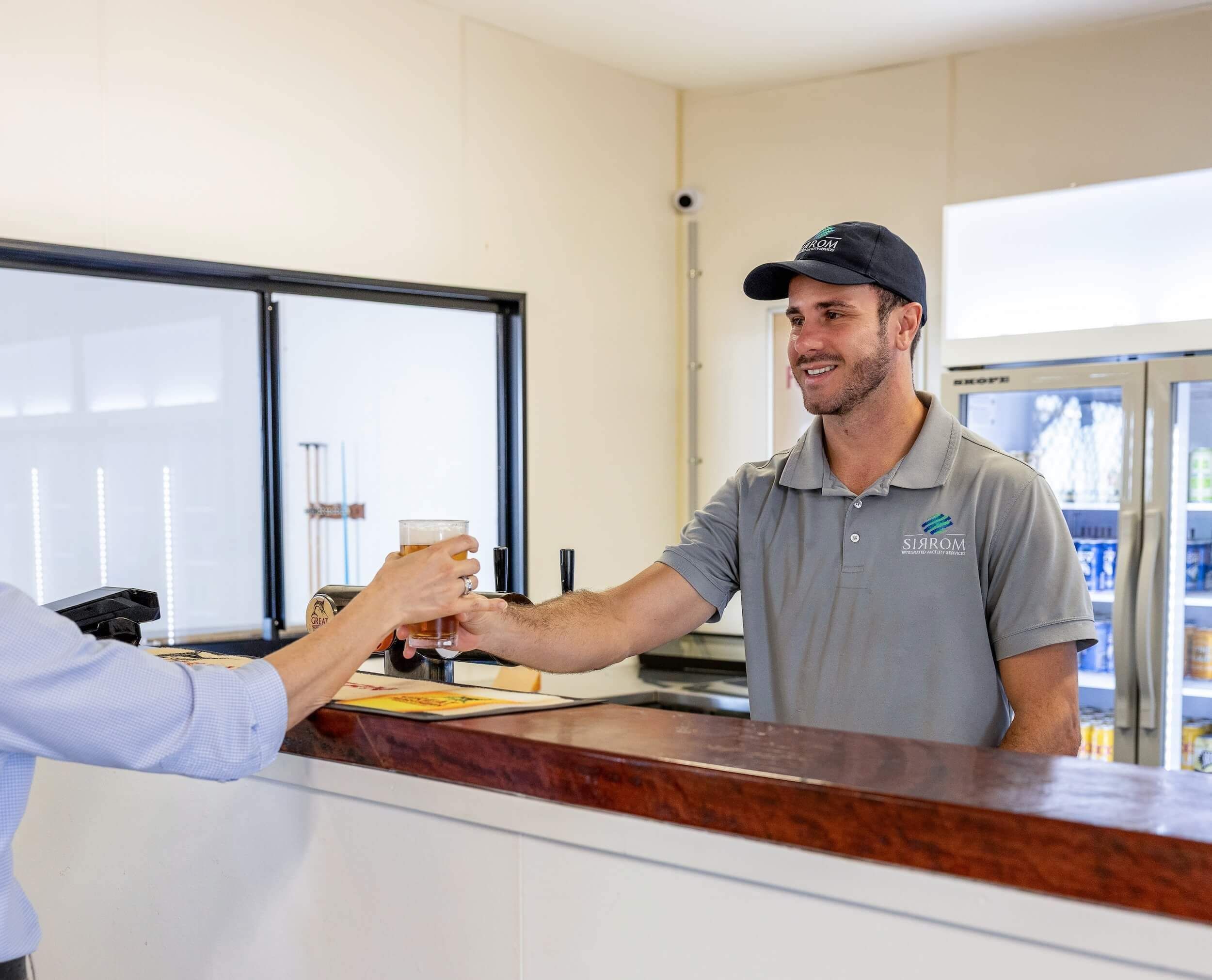 A bartender hands a patron a glass of beer across a counter in a tavern.
