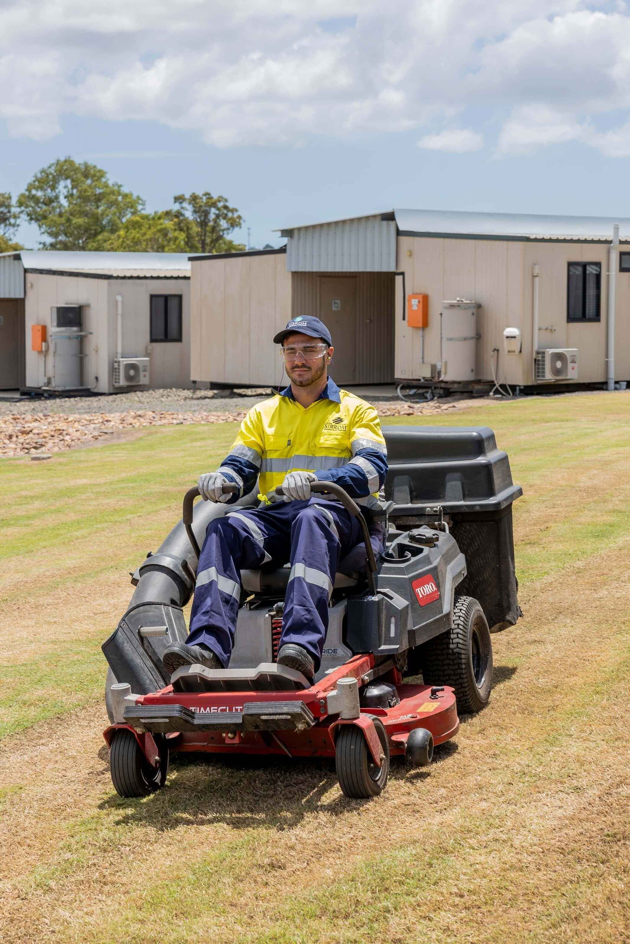 A young man safely operates a zero turn mower on a lawn.