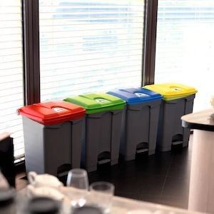 The pedal bins image, showing a row of four pedal bins, grey base and a red, yellow, blue and green lid in an office setting